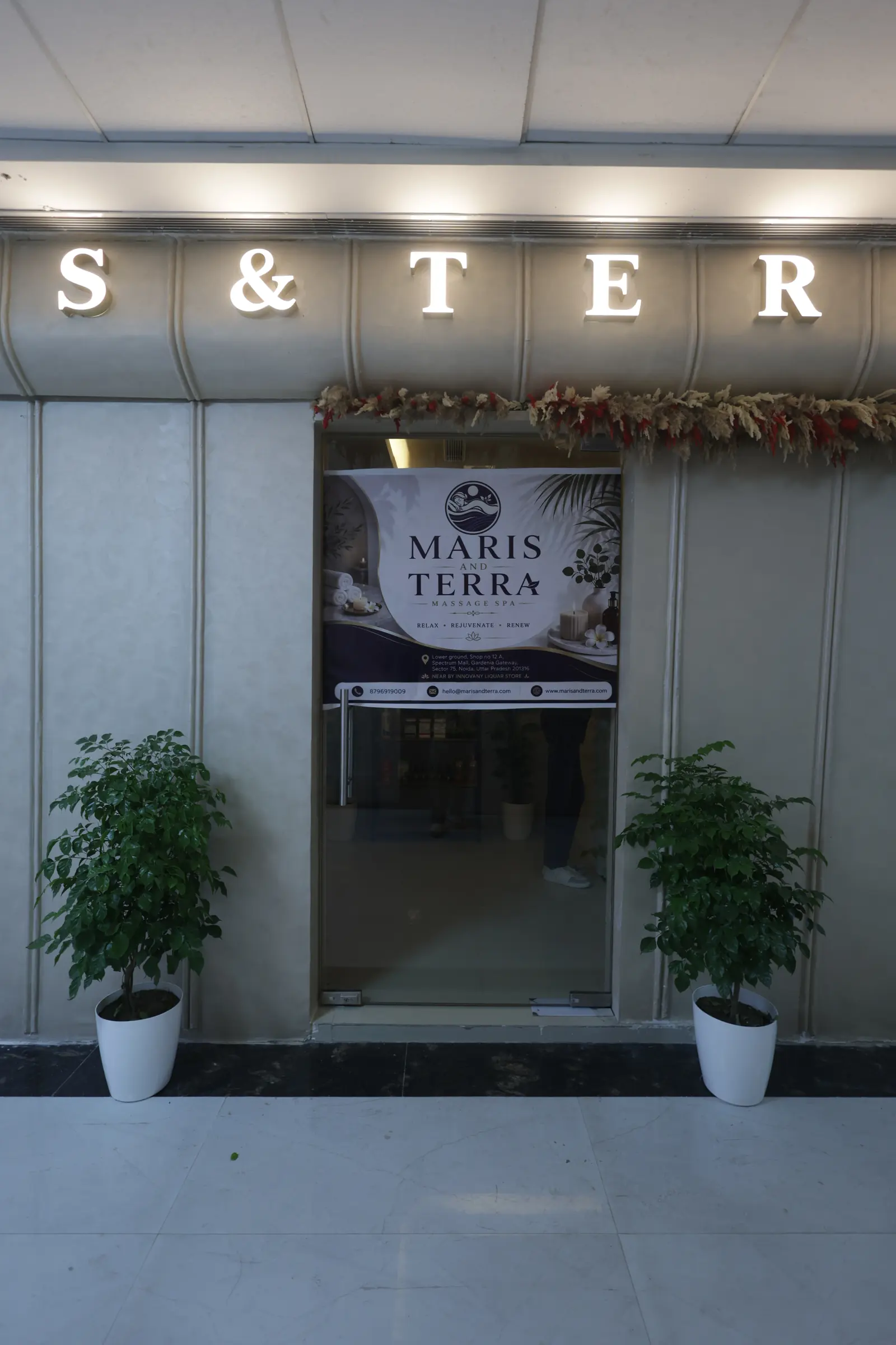 Glass entrance doors of Maris & Terra luxury spa at Spectrum Mall, Sector 75, Noida, framed by potted plants
